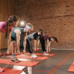 Fitness group performing exercises with dumbbells in a modern yoga studio setting.